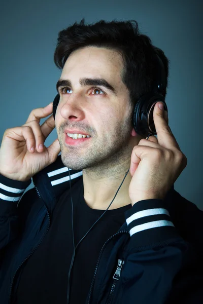 Pohledný mladý muž poslouchá hudbu ve sluchátkách — Stock fotografie