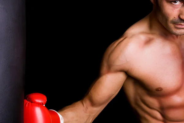 Sportovní mladý boxer Boxer boxovací pytel na černém pozadí — Stock fotografie