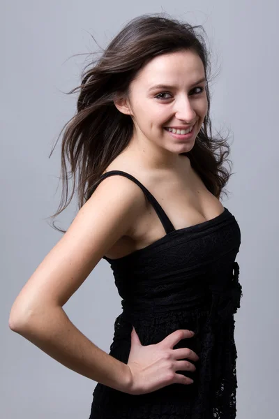 Vacker ung kvinna ler, mot en grå bakgrund — Stockfoto
