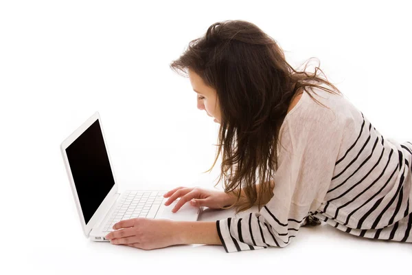 Schöne Frau auf dem Boden liegend, während sie mit einem Laptop arbeitet — Stockfoto