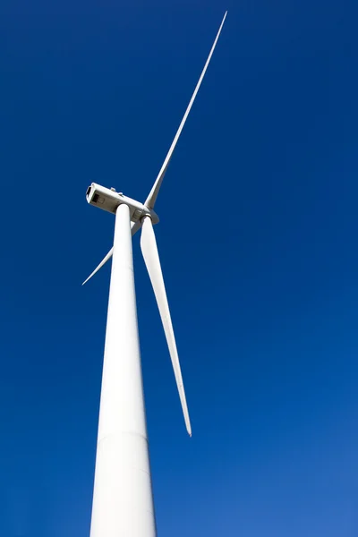 White wind turbine generating electricity on blue sky — Stock Photo, Image