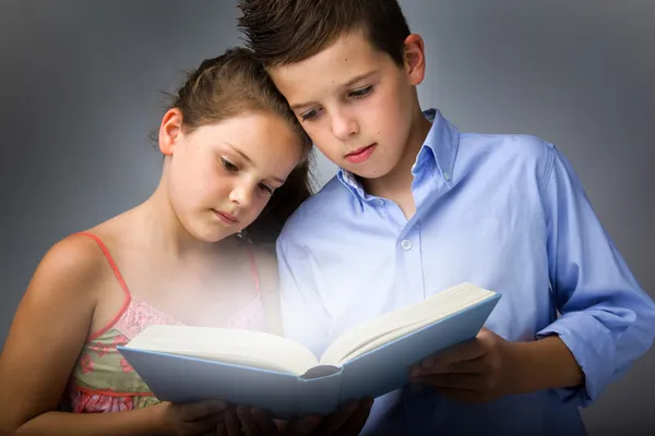 Imagen de niños inteligentes leyendo interesante libro —  Fotos de Stock