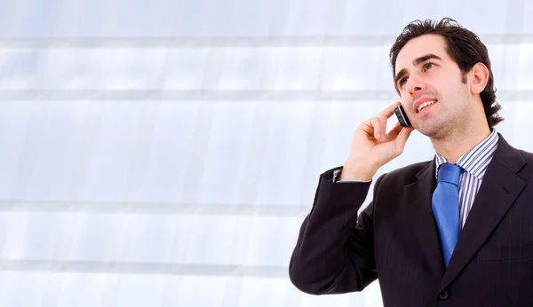 Ein junger, gutaussehender Geschäftsmann im Bürogebäude am Telefon — Stockfoto