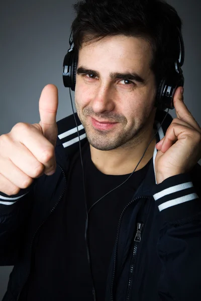 Pohledný mladý muž poslouchá hudbu ve sluchátkách — Stock fotografie