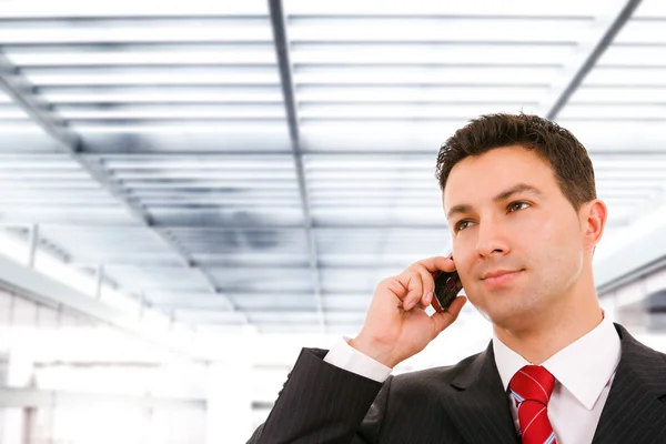 Een jonge, knappe zakenman op het kantoorgebouw op telefoon — Stockfoto