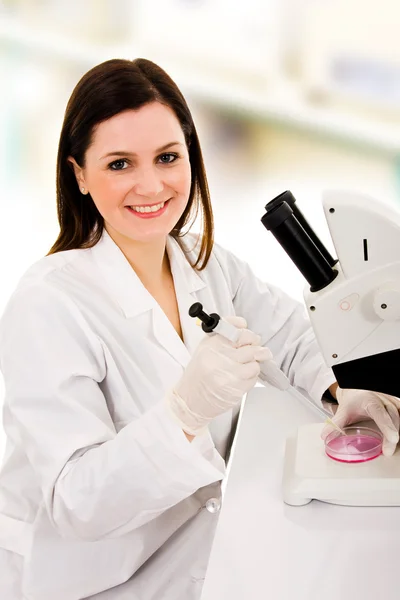 Cientista feminina sorridente usando um microscópio em seu laboratório — Fotografia de Stock