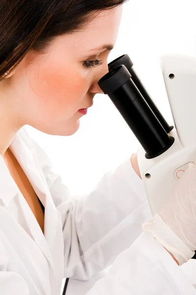 Любопытная женщина-исследователь смотрит на образец под микроскопом — стоковое фото