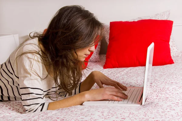 Молода красива жінка лежить на ліжку з ноутбуком — стокове фото