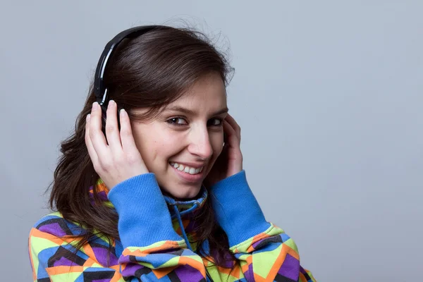 Usměvavá mladá žena poslechnout hudbu se sluchátky nad modrou bac — Stock fotografie