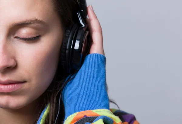 Jente som lytter til musikk mot grå bakgrunn – stockfoto