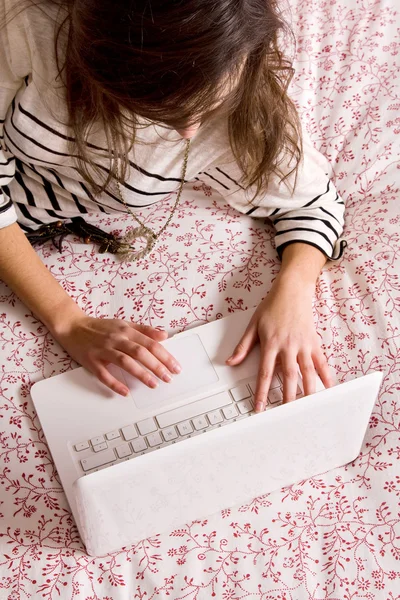 Jeune femme couchée sur le lit avec ordinateur portable — Photo