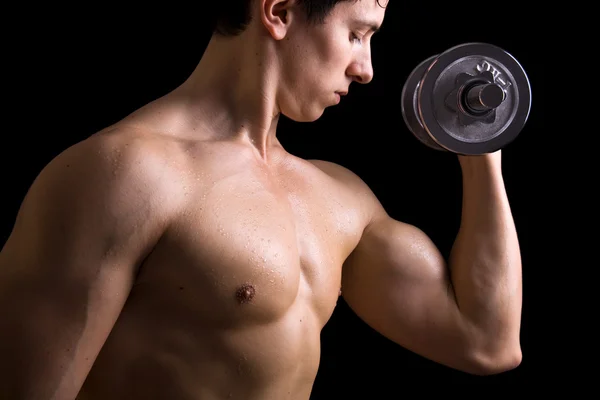 Muscular young man lifting dumbbells on black background. Royalty Free Stock Photos