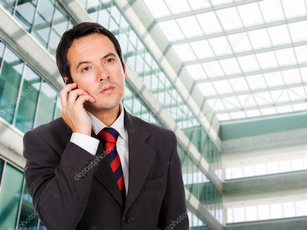 A handsome business man talking on the phone at his office build