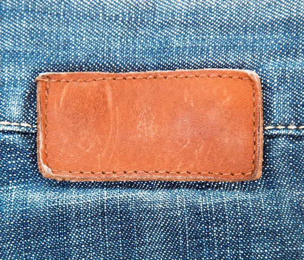 Etichetta dei jeans in pelle bianca cucita su blue jeans Immagine Stock