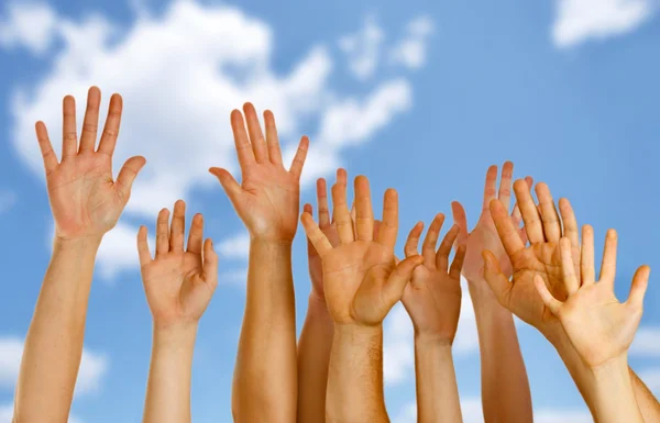 Mãos levantadas no ar através do céu azul — Fotografia de Stock
