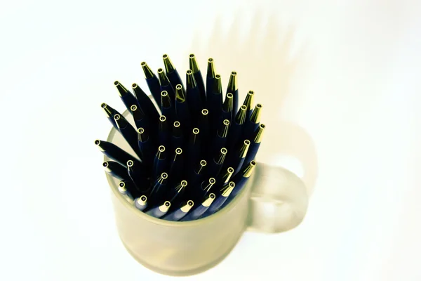 Bolígrafos metálicos en recipiente sobre fondo blanco — Foto de Stock