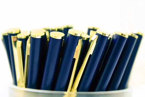 Bolígrafos elegantes en contenedor sobre fondo blanco — Foto de Stock