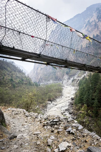 Hängande footbridge ower floden, nepal — Stockfoto