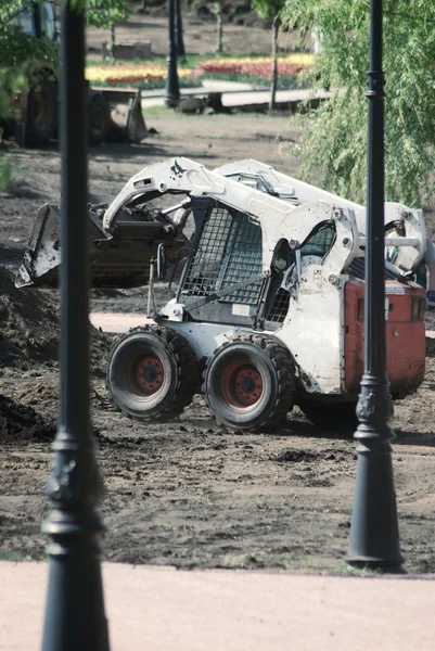 Mini excavadora de ruedas trabajando en el parque de la ciudad en la primavera —  Fotos de Stock