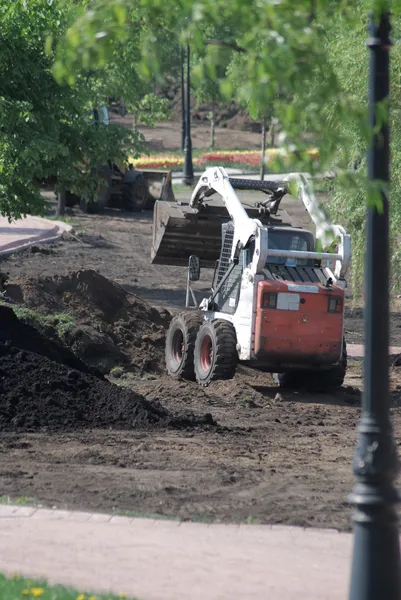 Mini wheel excavator working in city park at the spring — Stock Photo, Image