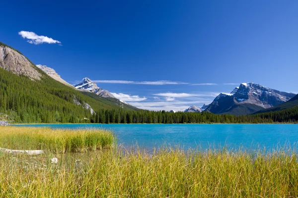Jezero s tyrkysově modrou vodou, rocky mountains a jasná obloha — Stock fotografie