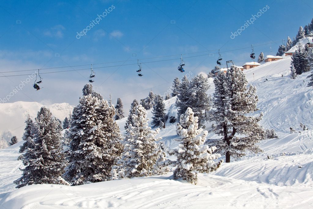 Chair ski lifts with skiers over blue sky in the mountains