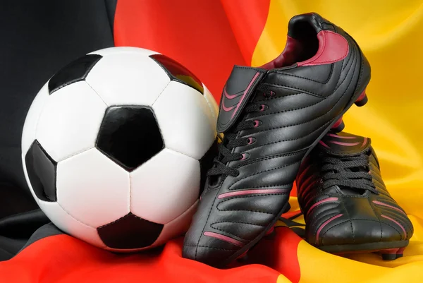 Fotbalový míč a boty na Německá vlajka — Stock fotografie