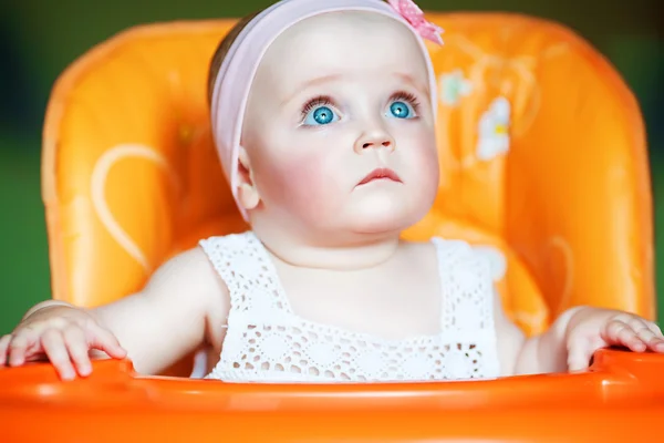 Carino bambino con gli occhi azzurri sulla sedia arancione — Foto Stock