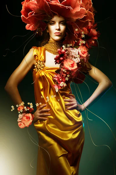 Sensuele mooie vrouw in lang gele jurk en bloemen — Stockfoto