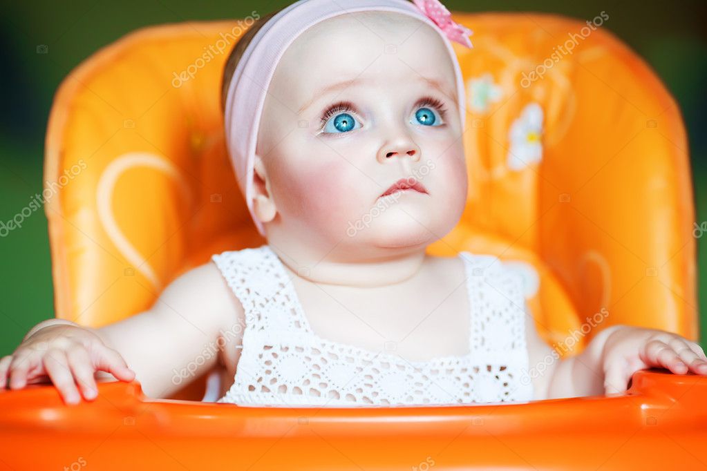 Cute baby with blue eyes in orange chair