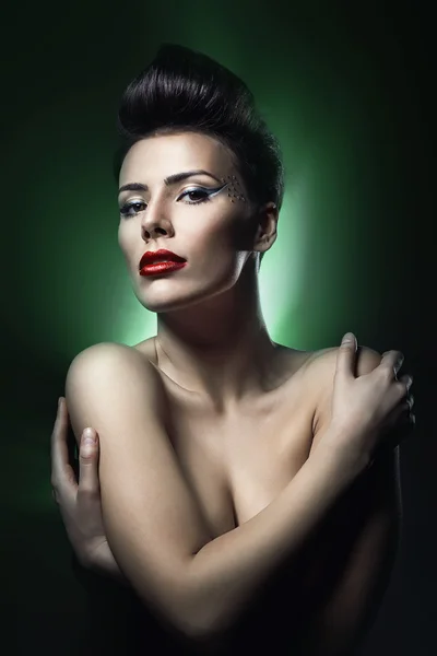 Brunette vrouw met rode lippen in donkere groen licht — Stockfoto
