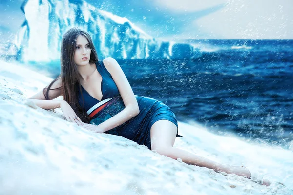 Kvinna i klänning på snöiga stranden och isberg — Stockfoto