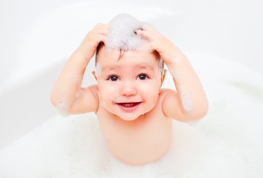 Happy child washing in a bathroom in foam clipart
