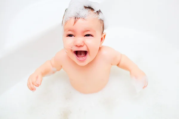 A criança pequena feliz banha-se em um banheiro — Fotografia de Stock