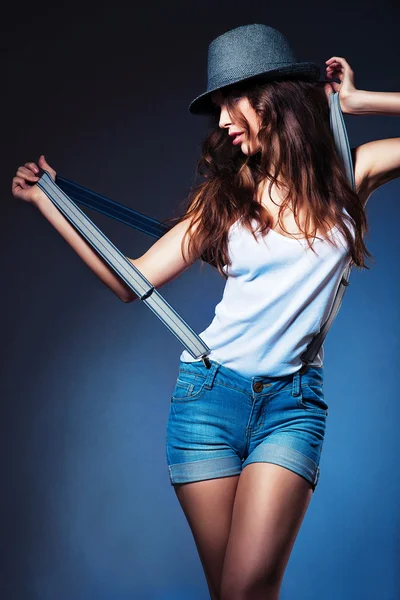Posing sexy woman in hat and shorts with suspenders in hands — Stock Photo, Image