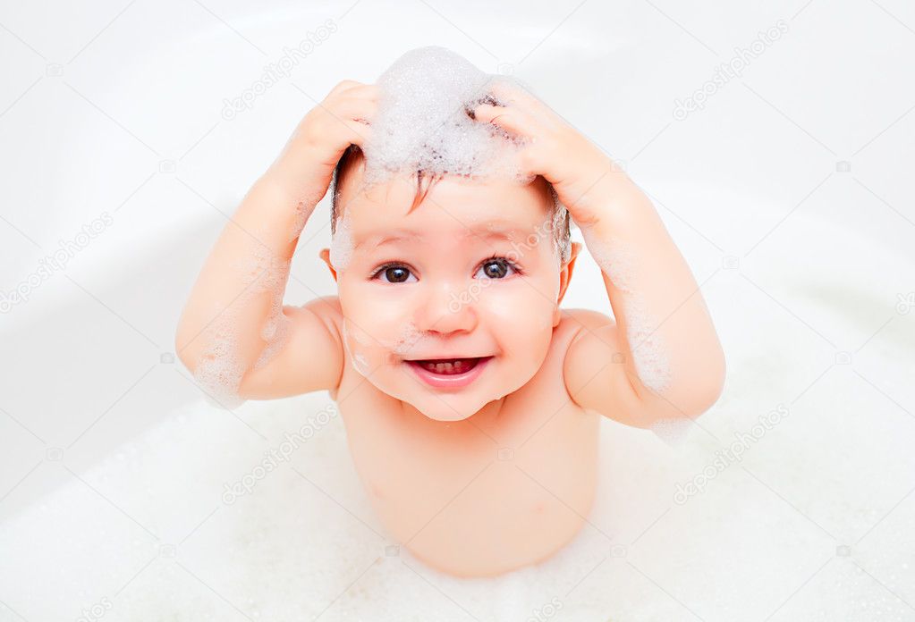 Happy child washing in a bathroom in foam