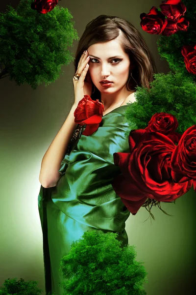 Attraktiv kvinna i grönt tyg med röda rosor — Stockfoto