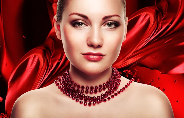 Bella mujer con accesorios sobre fondo de tela roja — Stockfoto
