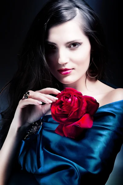 Mooie vrouw in blauwe weefsel met rode roos — Stockfoto