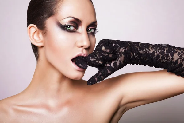 Nahaufnahme Porträt einer brünetten Frau mit schwarzem Handschuh im Mund — Stockfoto