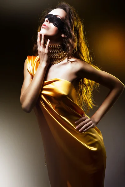 Sinnlich schöne Frau in goldenem Kleid und Maske — Stockfoto