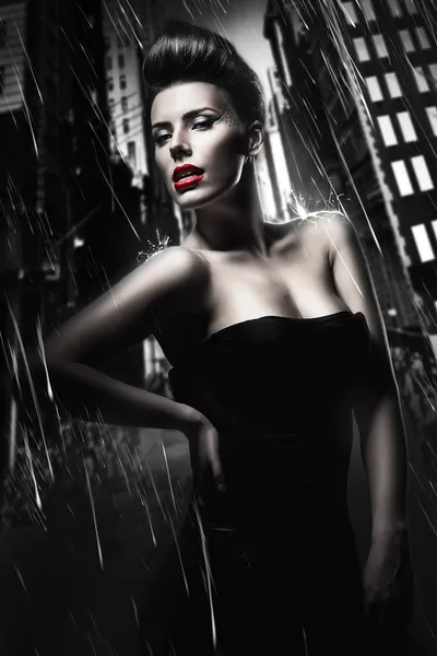 Sexy brünette Frau mit roten Lippen in der dunklen regnerischen Stadt — Stockfoto
