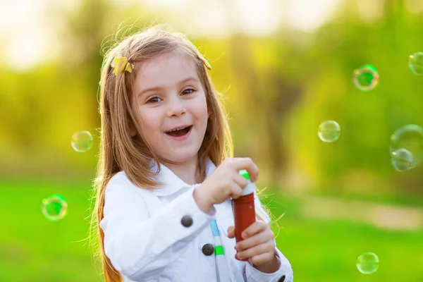 Lächelndes kleines Mädchen, das Seifenblasen pustet — Stockfoto