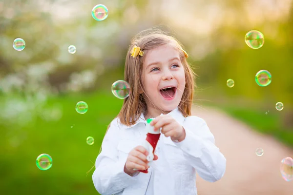 Glückliches kleines Mädchen, das Seifenblasen pustet — Stockfoto