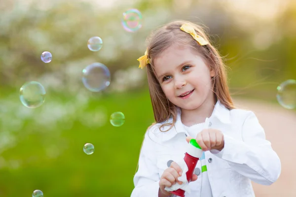 Kleines Mädchen pustet Seifenblasen — Stockfoto
