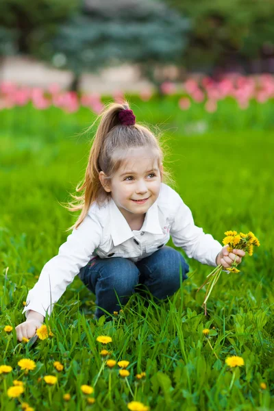 Счастливый ребенок, сидящий на зеленом лугу — стоковое фото