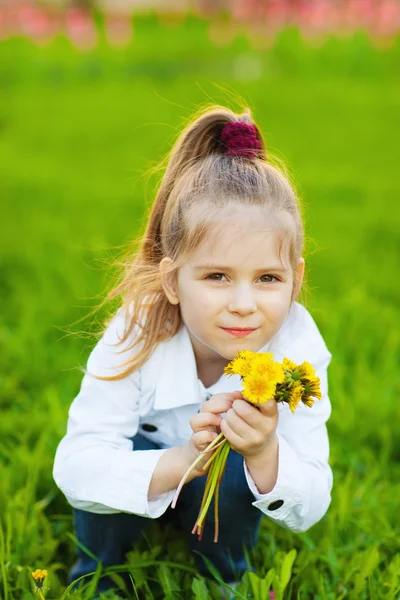 Cute little girl with dandelions in spring day — Stock Photo, Image
