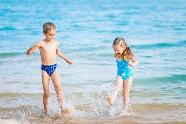 Happy kids playing at the beach shore