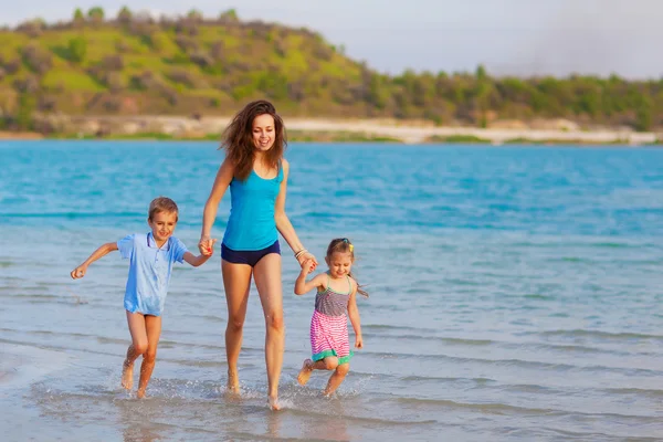 Mother with children running at the beach — Stock Photo, Image