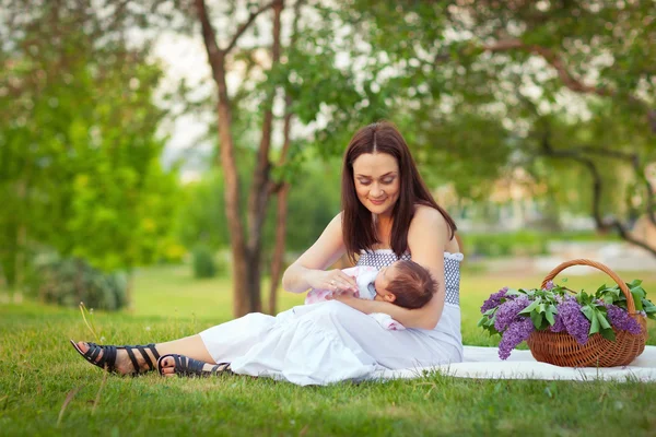 Happy mother and baby resting in summer park — Stock Photo, Image